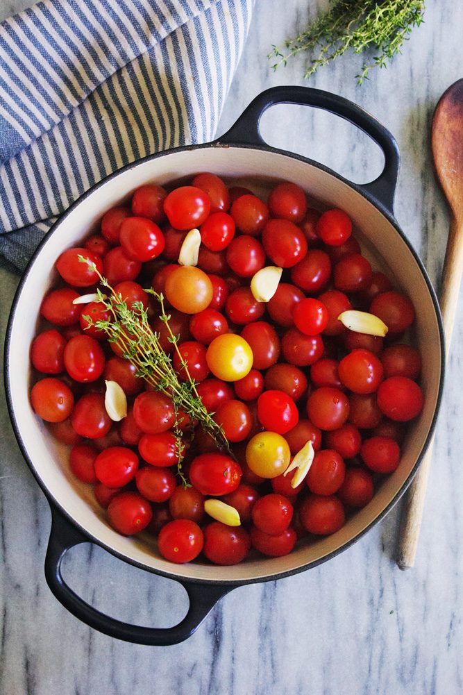 Dutch oven filled with fresh cherry tomatoes, garlic, herbs
