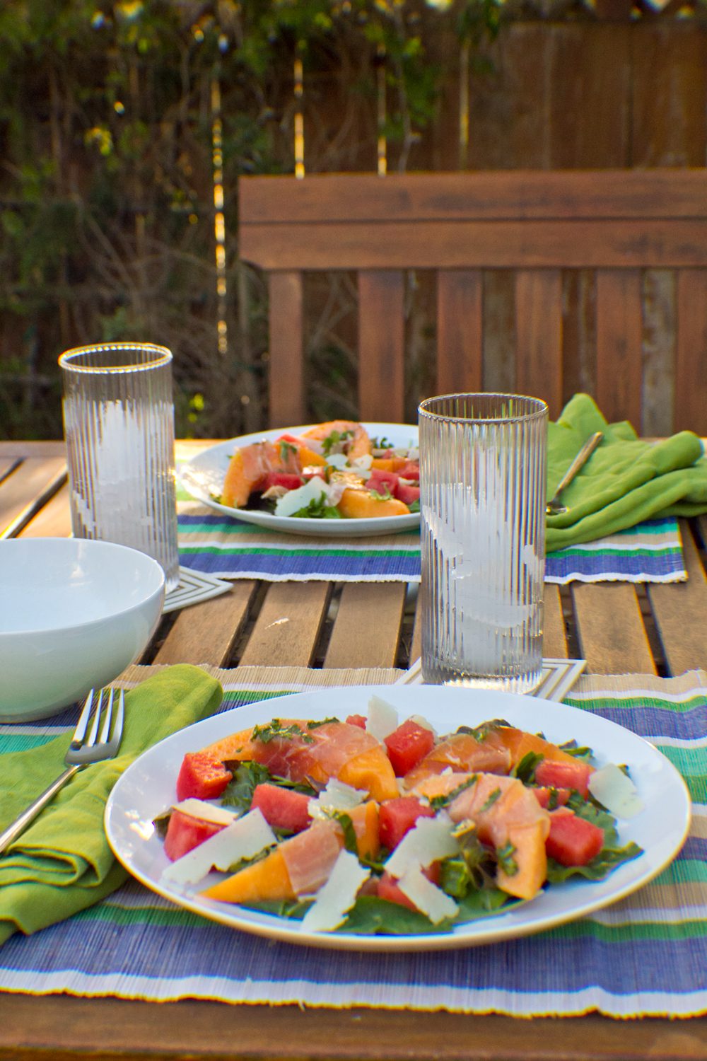 Two meal settings at outdoor table with Melon + Nectarine Prosciutto Summer Salad