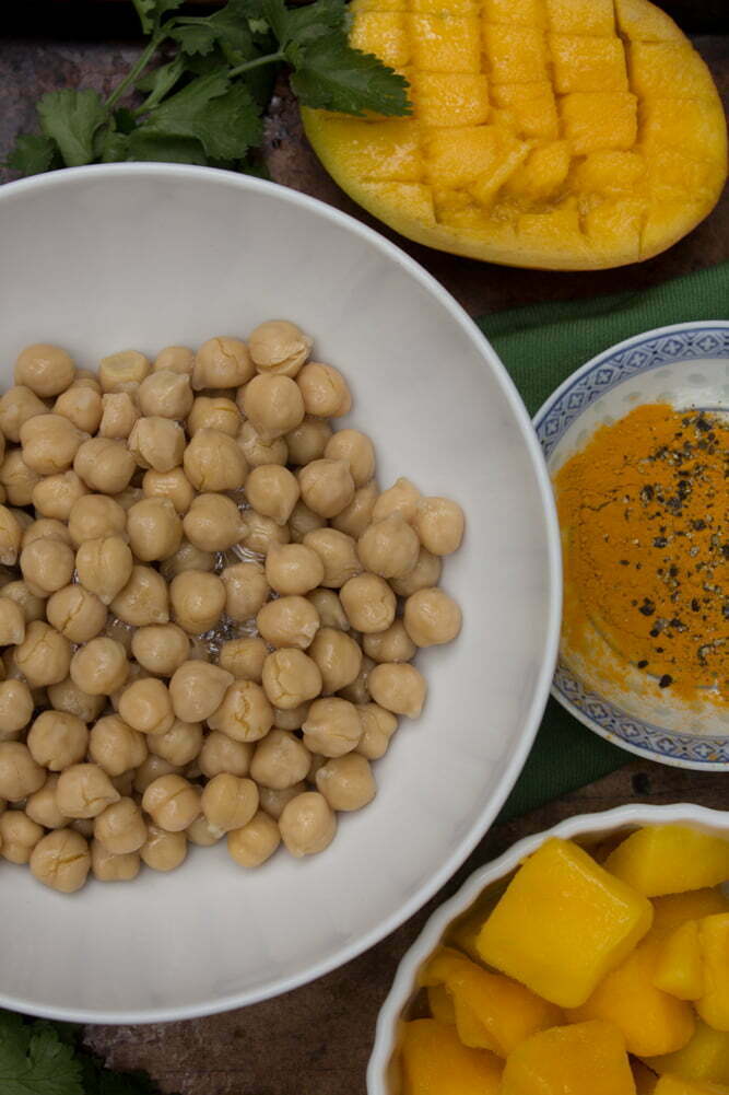 MangoTurmericHummus_2web Fresh ingredients from Mango Turmeric Hummus | Bowl of chickpeas, frozen and fresh mango, turmeric with fresh cracked pepper, and cilantro