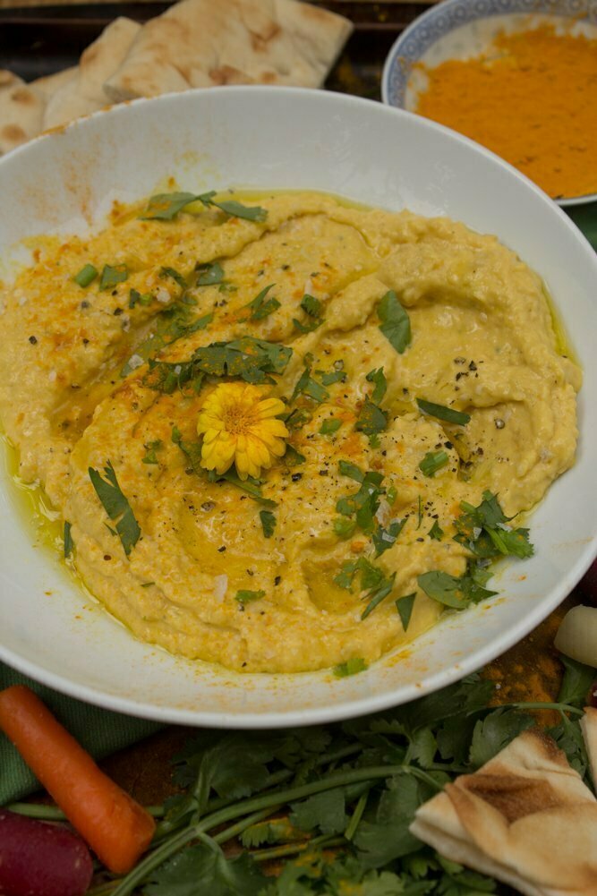 MangoTurmericHummus_7web Close up view of plated mango turmeric hummus garnished with fresh cilantro and edible flower