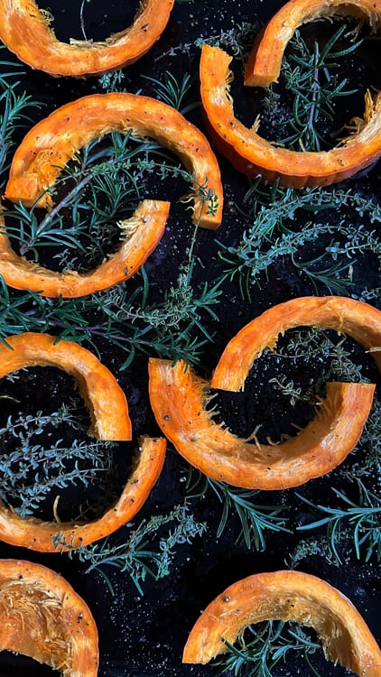 Honey Thyme Pumpkin Hummus | Slices of small pumpkin placed on a baking sheet seasoned with olive oil, salt and pepper, and placed upon fresh thyme and rosemary.