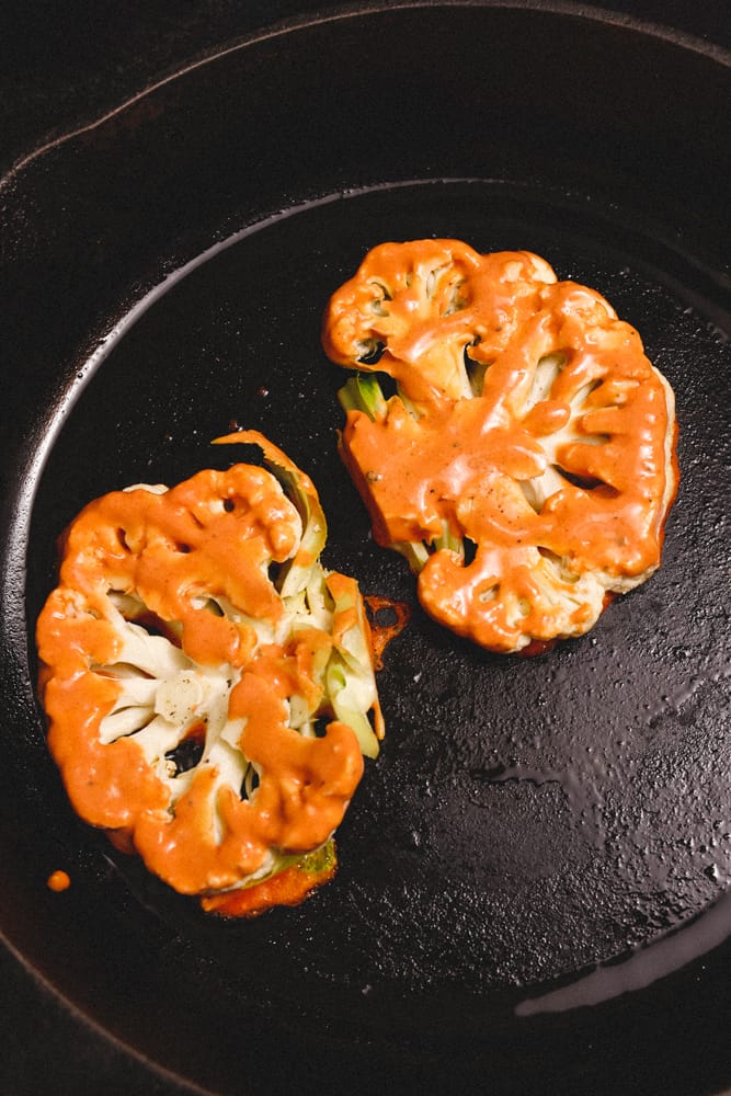 Spicy Cauliflower steaks cooking in cast iron pan.