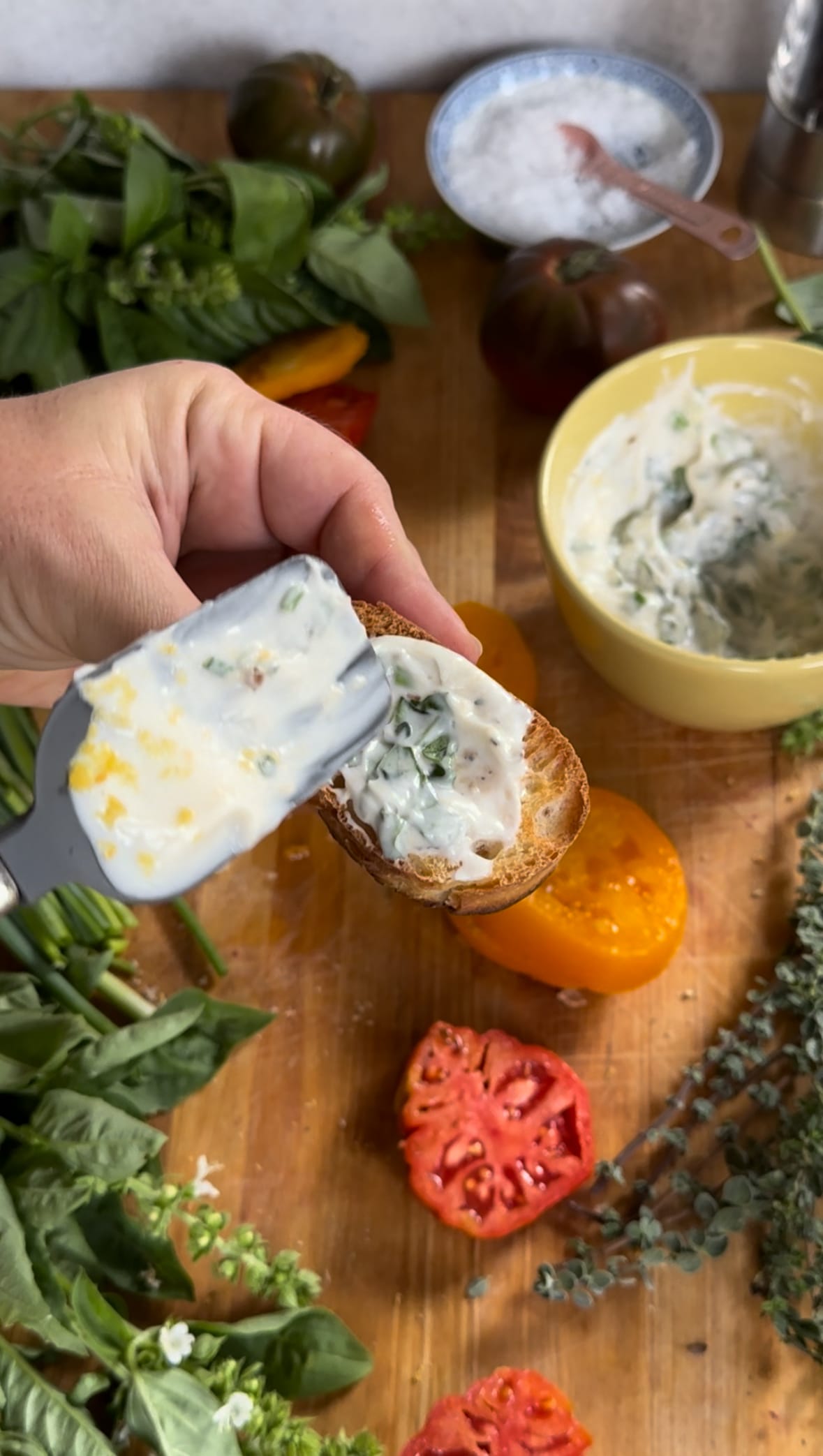 Smearing herby mayo on toasted French bread for Summer Tomato Crostini