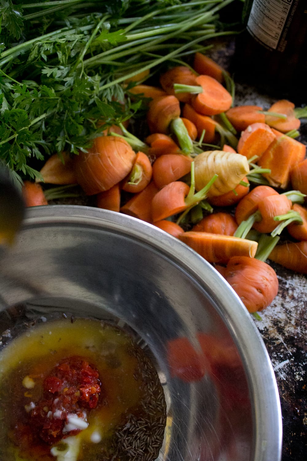 Garden-fresh carrots trimmed of their greens and sliced. Harissa and honey marinade for the soon-to-be roasted carrots.