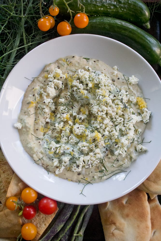 Tzatziki-inspired hummus with marinated feta crumbles served with flatbread, crispy pita chips, sweet cherry tomatoes, summer beans, and cucumber